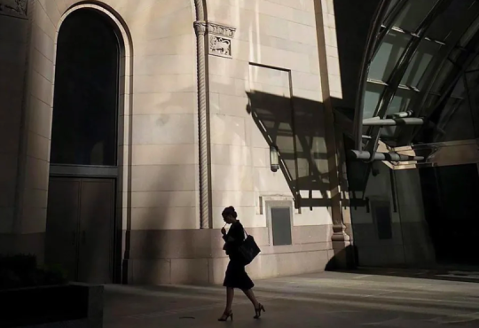 Silhouetted woman walking through business district