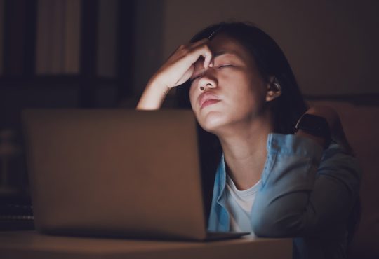 Stressed woman working at computer at night