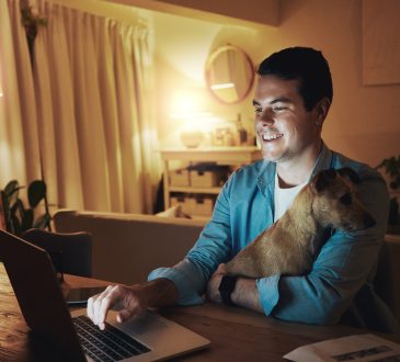 Man working on laptop at home with dog in lap