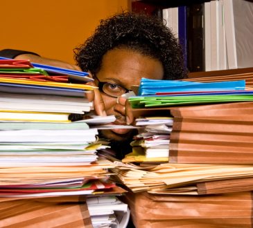 Person behind two large stacks of files