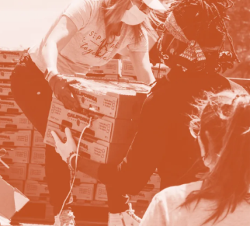 Two women unloading boxes of food from truck