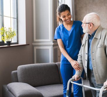 Nurse helping elderly man using walker