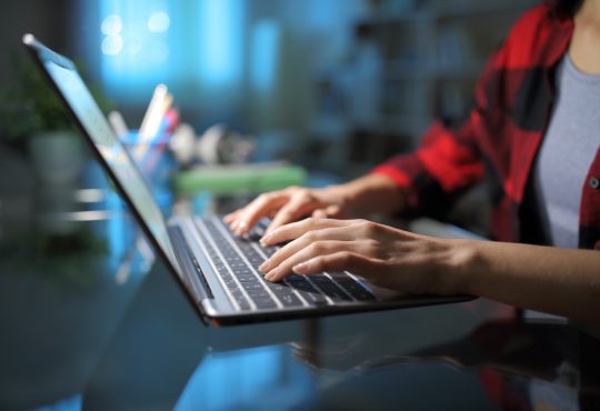 Hands typing on laptop