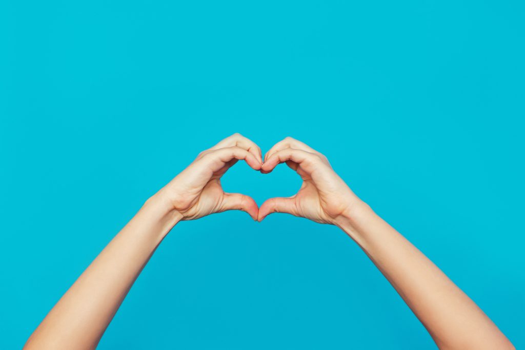 Hands making heart on blue background