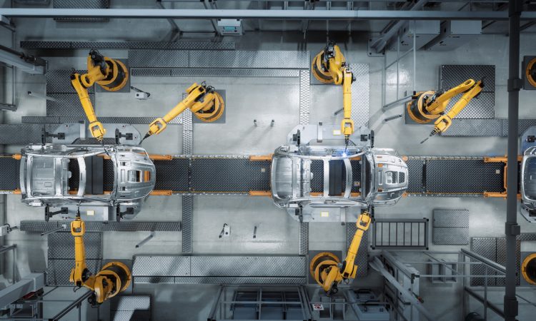 Aerial view of robot arms assembling cars in factory