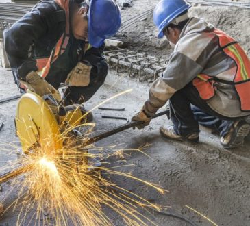 Two construction workers cutting pipe