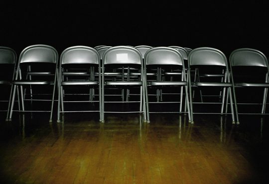 Rows of empty chairs in dark room on wooden floor