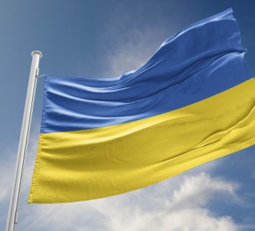 Ukrainian flag against blue sky with clouds