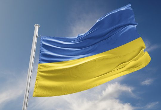 Ukrainian flag against blue sky with clouds