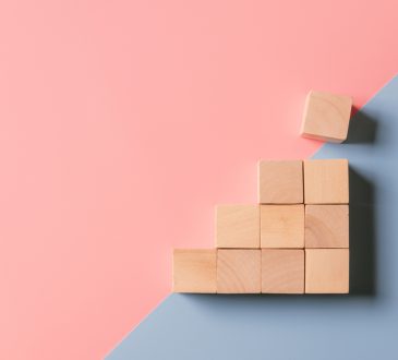 Stack of wooden blocks on pink and blue background