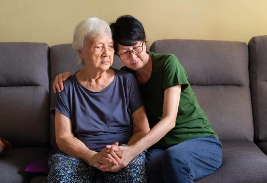 Woman sitting on couch with her elderly mother