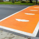 Crosswalk painted orange with white feathers for Truth and Reconciliation