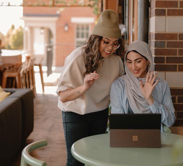 Two women looking at laptop on cafe patio