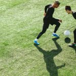 tWO MEN PLAYING SOCCER ON FIELD OUTDOORS