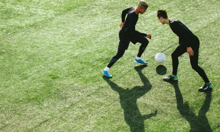tWO MEN PLAYING SOCCER ON FIELD OUTDOORS