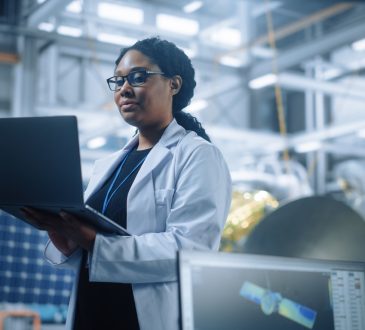 Woman engineer wearing lab coat and holding computer