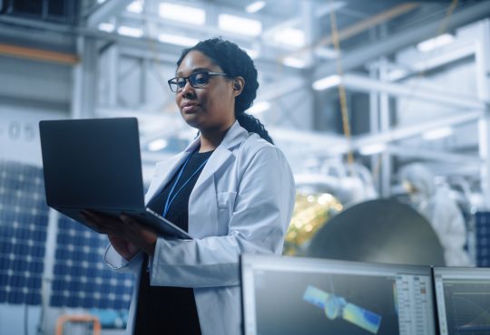 Woman engineer wearing lab coat and holding computer