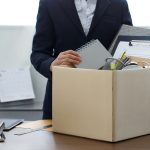 Person seen from neck down packing up belongings into cardboard box in office