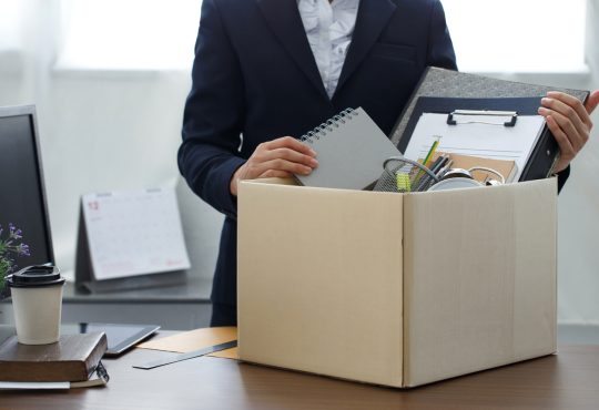 Person seen from neck down packing up belongings into cardboard box in office