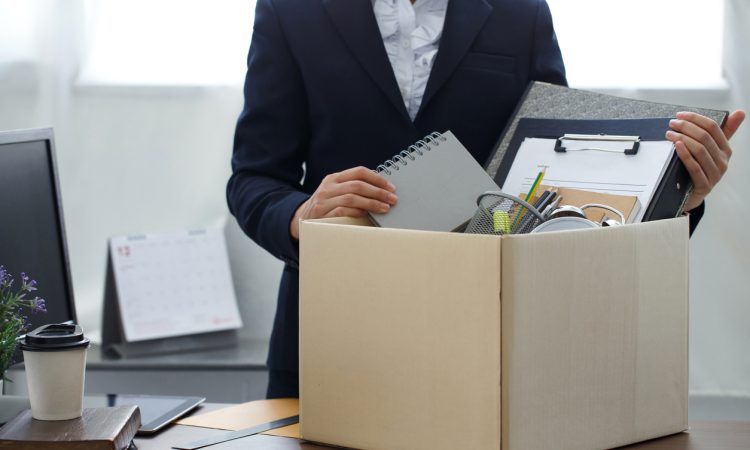 Person seen from neck down packing up belongings into cardboard box in office