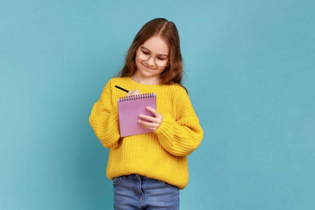 Girl standing and writing in notebook