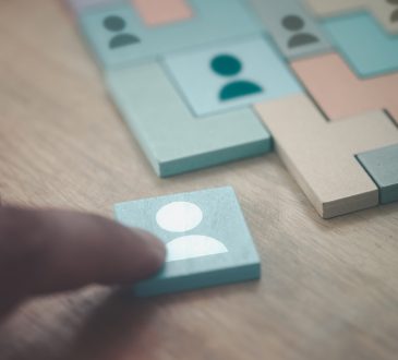 Hand building puzzle from wooden tiles with people icons on them