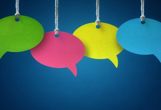 Blank colorful speech bubbles hanging from a cord over blue background