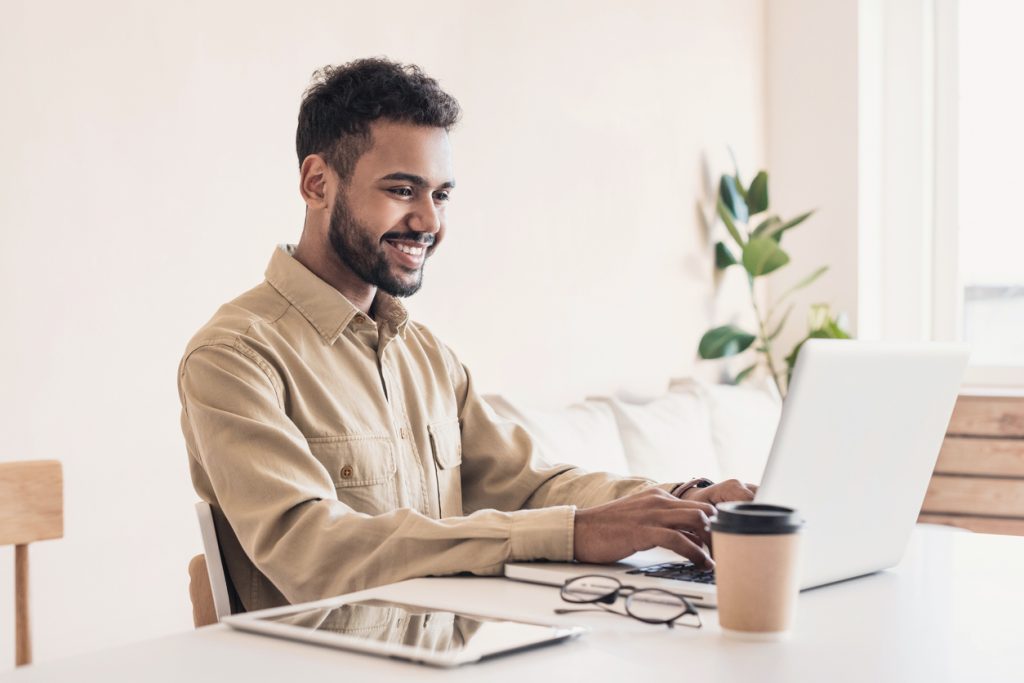 Man smiling while working on laptop at home.