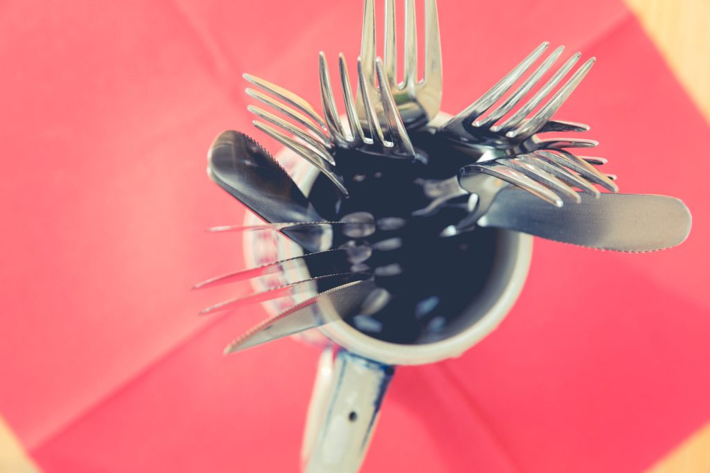 Bird's-eye view of mug full of cutlery on pink background