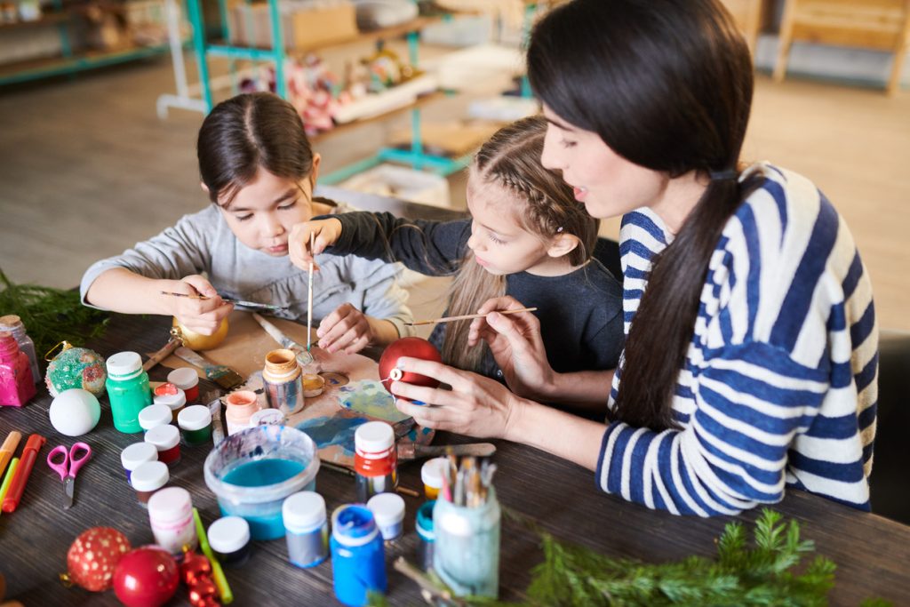 Two girls painting with mom