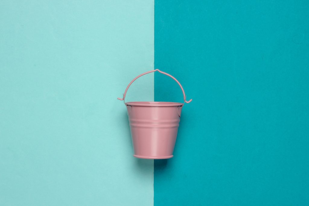 Pink empty mini bucket on blue pastel background.