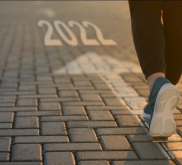 Person's feet walking on interlocking brick pathway with arrow and "2022" underneath