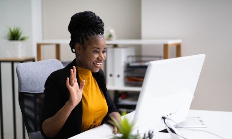 Woman waves at computer during video call