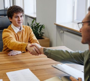 Two men shaking hands across table.