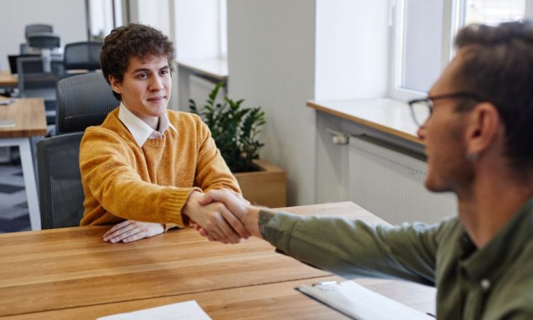 Two men shaking hands across table.