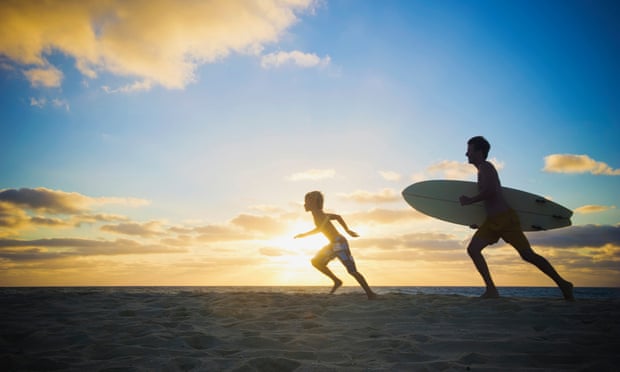 Man running with surfboard on beach