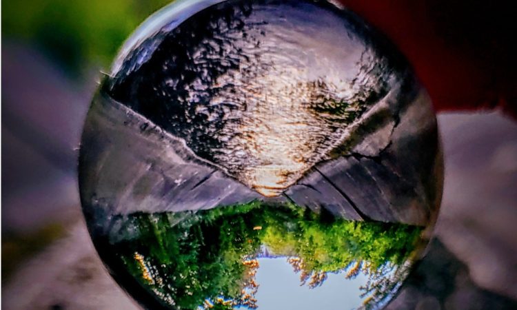 Image of river and forest seen through clear glass marble