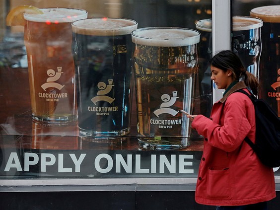 Woman walking by storefront with "APPLY ONLINE" in window