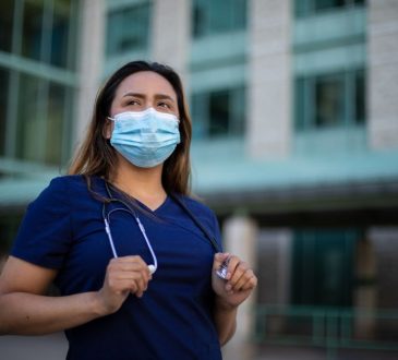 Doctor wearing scrubs, mask and stethiscope outside of hospital