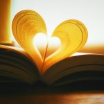 Book silhouetted by sun with middle pages folded into shape of a heart