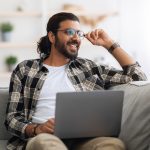Man sitting on couch working on laptop