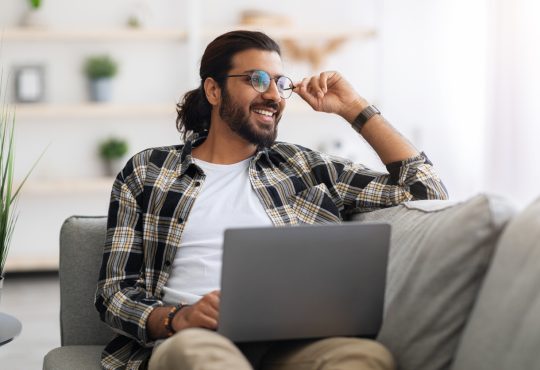 Man sitting on couch working on laptop