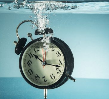 Black clock with white face sinking in water
