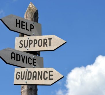 Signpost on background of blue sky with arrows reading "Help," "Support," "Advice" and "Guidance"