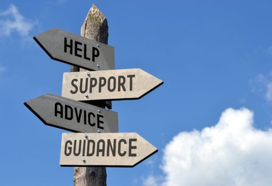 Signpost on background of blue sky with arrows reading "Help," "Support," "Advice" and "Guidance"