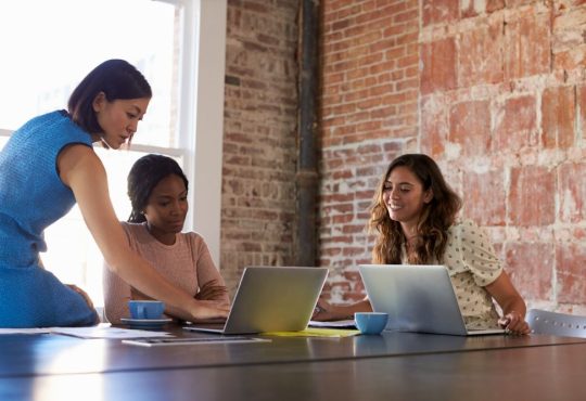 Three women working at table in office