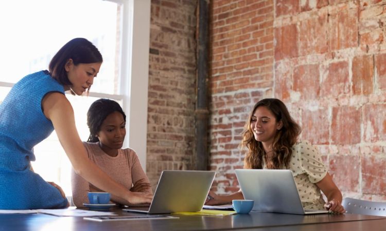 Three women working at table in office