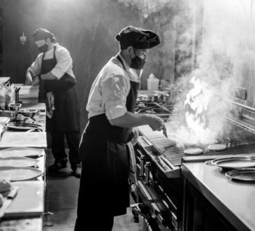 Black and white image of two chefs cooking in restaurant kitchen