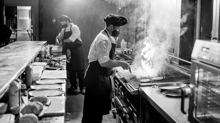 Black and white image of two chefs cooking in restaurant kitchen