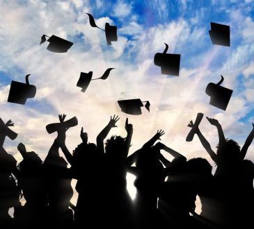 Silhouetted image of group of people throwing graduation caps in the air outside